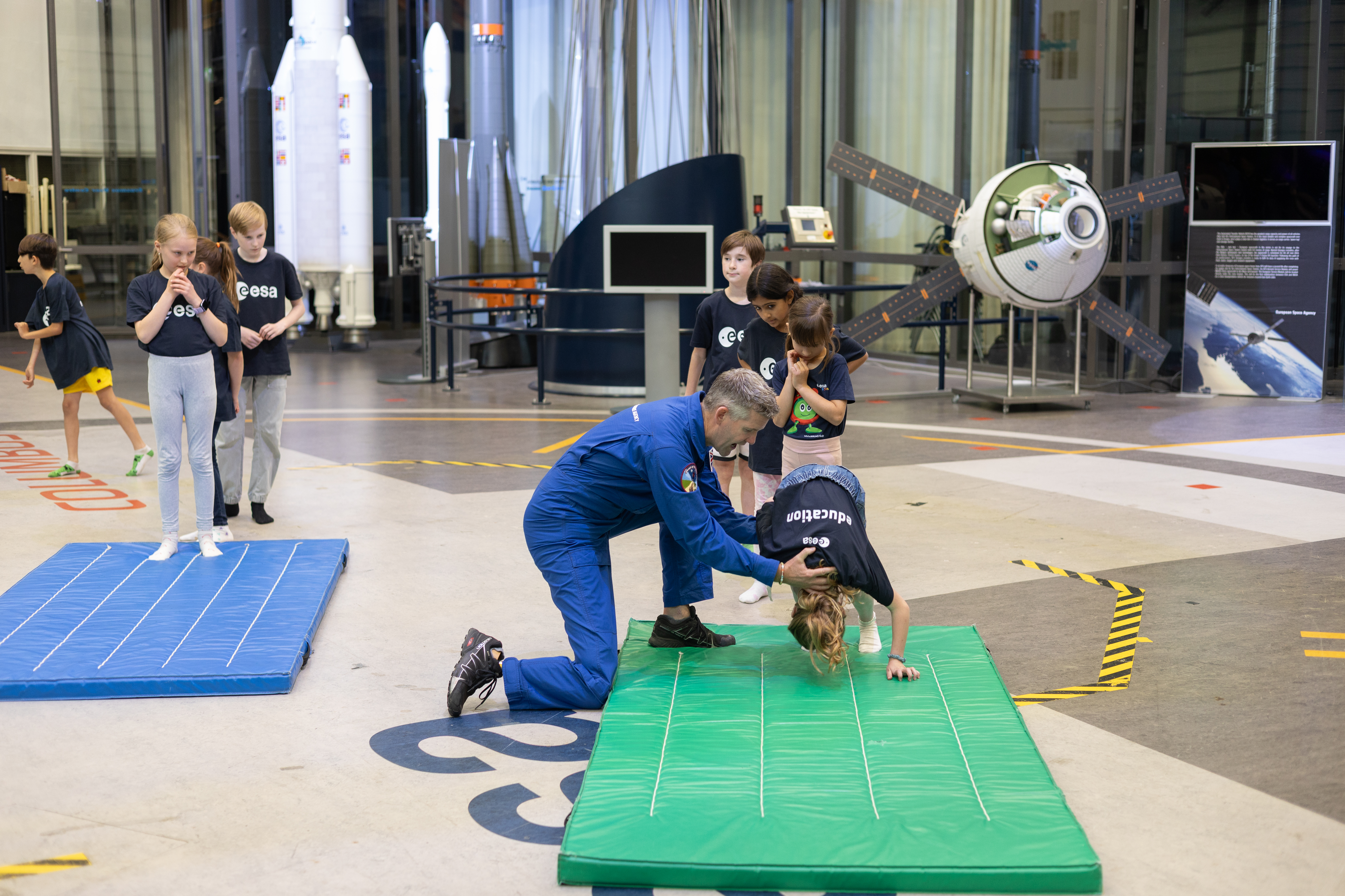 John McFall, member of the ESA astronaut reserve, helps a Mission X participant perform a front roll
